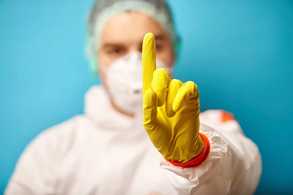 Arzt in Schutzanzügen zeigt Zeigefinger nach oben, signalisiert Gefahr, warnt vor Quarantäne. — Stockfoto