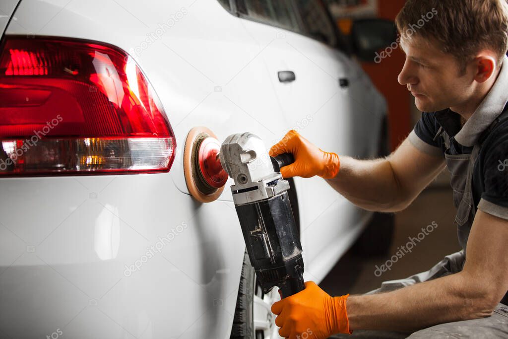 Polishing white car, close-up. A man polishes the automobile from scratches.