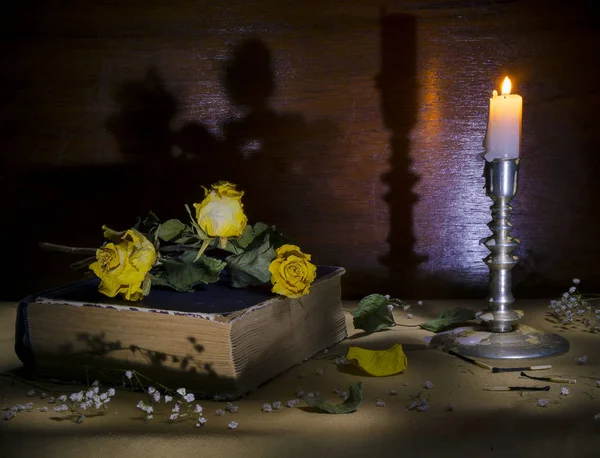 Kitap, bir mum yanan bir mum ile yatan natürmort eski Sarı Gül.