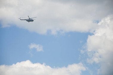 Helikopter bulutlu mavi bir gökyüzüne doğru uçuyor.