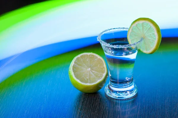 tequila with salt and lime slice on the background of colored stripes