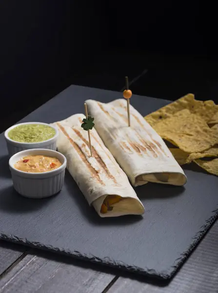  Burrito peynir soslar ve Guakamole siyah arka plan ile.