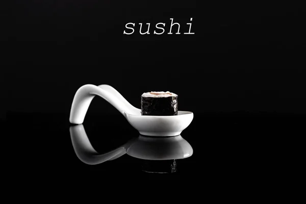 Suşi 0n beyaz kaşık siyah arka plan ile.
