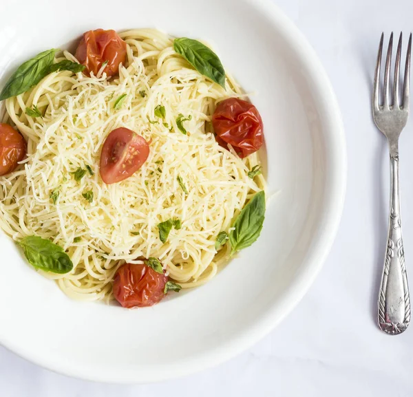 Tabak spagetti domates, fesleğen ve rendelenmiş peynir ile