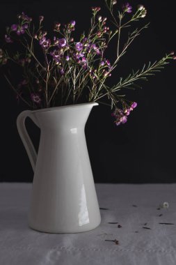 Çiçek ve siyah arka plan ile beyaz vazo.