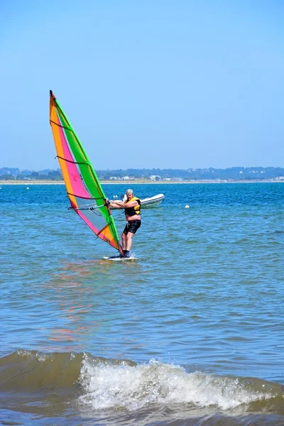 Windsurfer paardrijden de golven in de buurt van het strand, Studland Bay. — Stockfoto