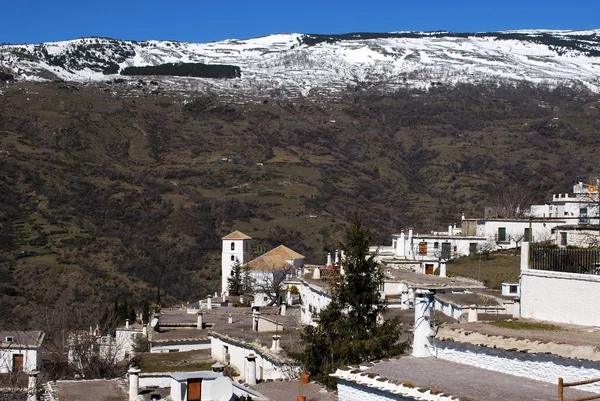 Vista geral sobre os telhados da cidade em direção às montanhas cobertas de neve, Bubion, Espanha . — Fotografia de Stock