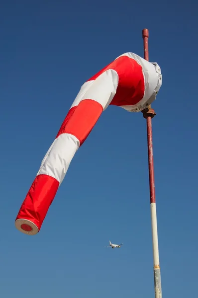 Windsock with A320 aeroplane to the rear against  blue sky. — Stock Photo, Image
