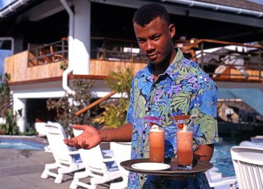 Grafton Beach Resort, Stonehaven Bay, Tobago'da bir tepsi kokteyl tutan otel garsonu.