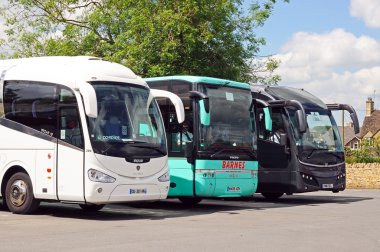 Üç turist antrenörleri bir otobüs ve otopark, Bourton Su üzerinde üst üste park.