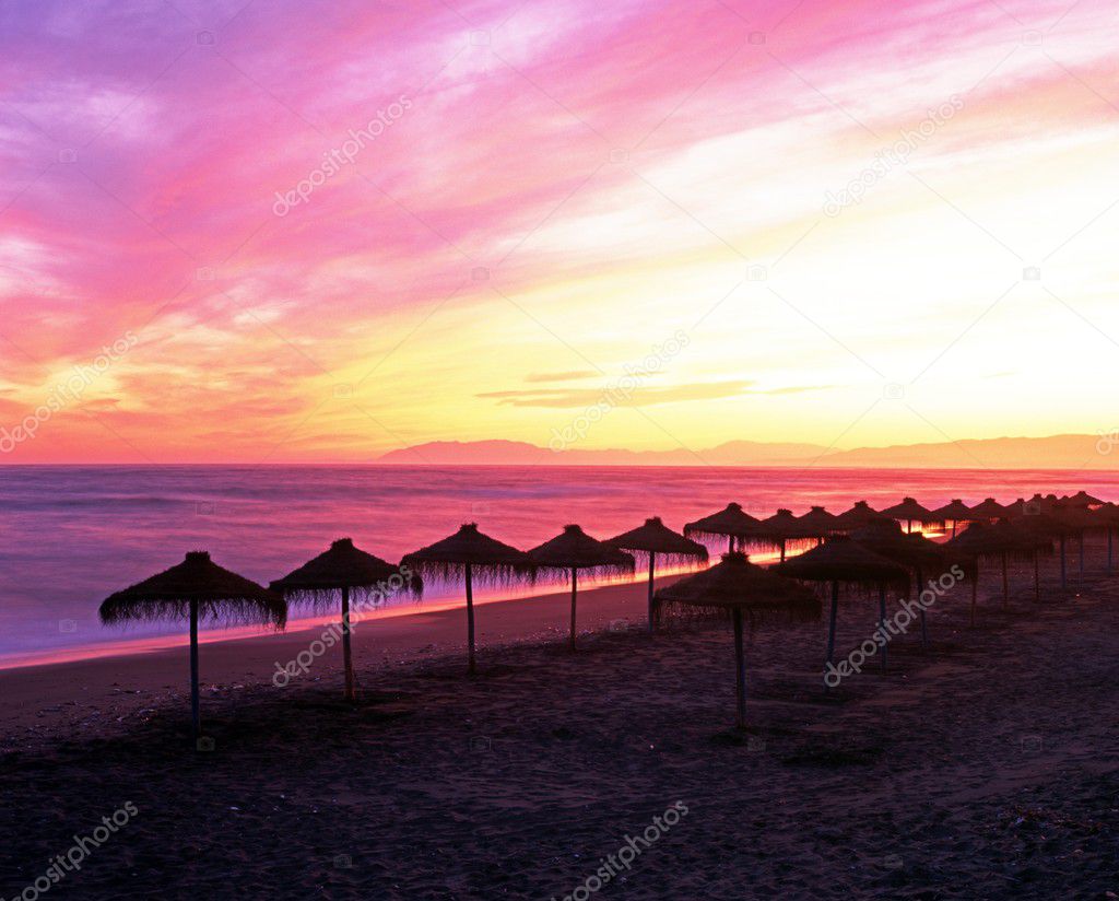 Parasols on beach at sunset, Torrox Costa, Spain.