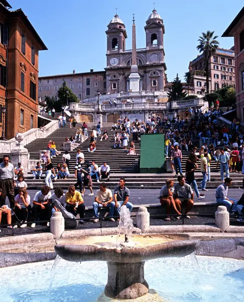 Turister som sitter på Spanska trappan med en fontän i förgrunden, Rom, Italien. — Stockfoto