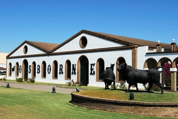 Вид на Осборн Бодега (Bodega El Tiro) со статуей быка на переднем плане, El Puerto de Santa Maria, Испания . — стоковое фото