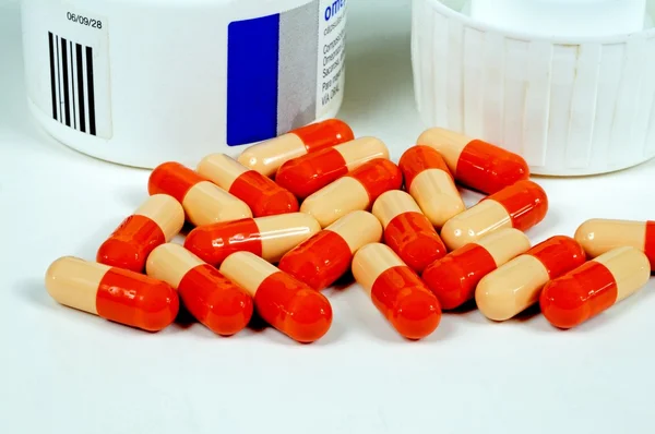 Omeprazole tablets in capsules with a container to the rear. — Stock Photo, Image