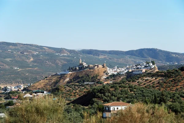 Vista da cidade com a igreja no topo do morro e olivais nas montanhas para trás, Iznajar, Espanha . — Fotografia de Stock