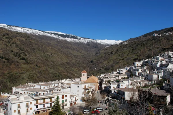 Blick über das weiße Dorf auf die schneebedeckten Berge der Sierra Nevada, Pampaneira, Spanien. — Stockfoto