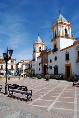 Dar görüşlü Merkezi (Centro Parroquial) bir dövme demir sokak lambası ve tezgah ön planda, Plaza del Socorro, Ronda, İspanya.