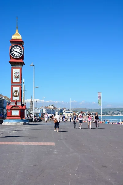 Vista a lo largo del paseo marítimo y la costa con la torre del reloj Jubileo Reina Victorias en primer plano, Weymouth . —  Fotos de Stock