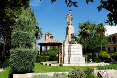 Bandstand and religious monument in the gardens in front of the Parish of our Lady of the Assumption church, Priego de Cordoba, Spain. clipart