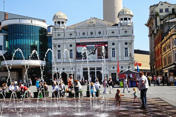 På Playhouse teater i Williamson Square med fontäner i förgrunden och människor njuter av sommarvärmen, Liverpool, Storbritannien. — Stockfoto