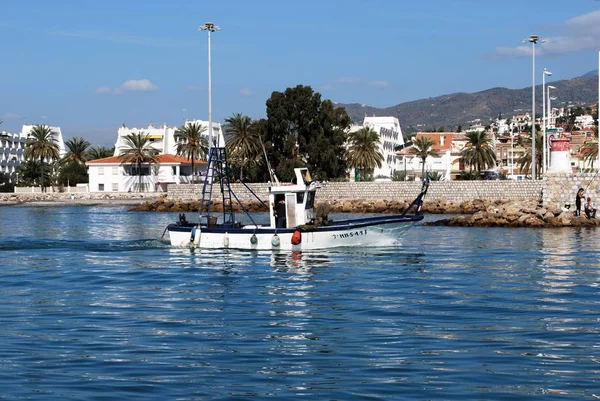 Традиционное рыболовное судно, заходящее в гавань с апартаментами сзади, Калета-де-Велес, Испания . — стоковое фото