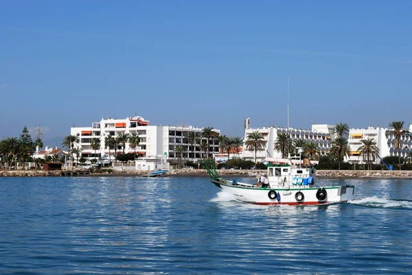 Traditionell fiskebåt lämnar hamnen med byggnader till baksidan, Caleta de Velez, Spanien. — Stockfoto
