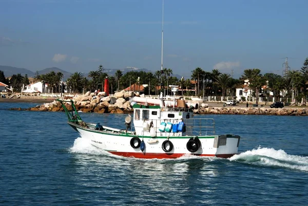 Barco pesquero tradicional que sale del puerto con edificios en la parte trasera, Caleta de Vélez, España . — Foto de Stock
