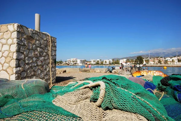 Рыболовные сети на набережной с парой, сидящей на краю гавани с видом на море, Калета-де-Велес, Испания . — стоковое фото