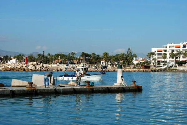 Fiskebåt in hamnen med fiskare på kajen i förgrunden, Caleta de Velez, Spanien. — Stockfoto