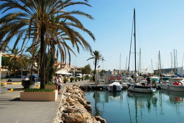 Yachts förtöjd i småbåtshamnen med strandpromenaden till vänster sida, Caleta de Velez, Spanien. — Stockfoto