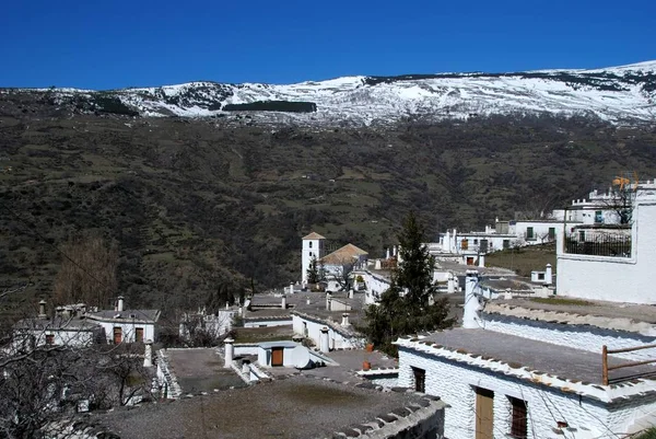 Vista geral sobre os telhados da cidade em direção às montanhas cobertas de neve, Bubion, Espanha . — Fotografia de Stock