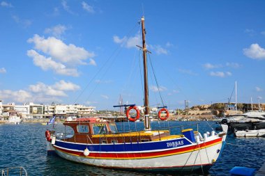 Arka tarafa, Hersonissos, Crete watefront binaları ile limanında demirlemiş geleneksel Yunan yat.