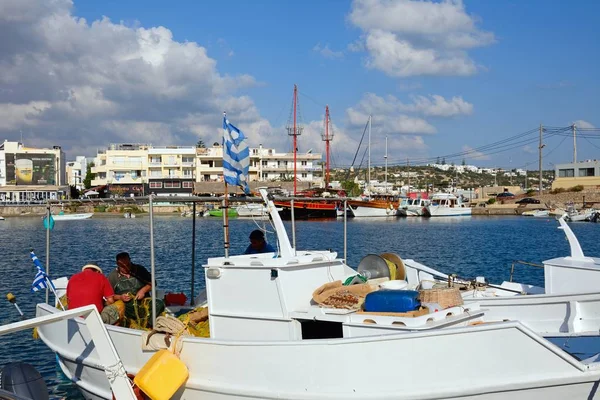 Рыбаки на своей традиционной рыбацкой лодке в порту с ресторанами на набережной в задней части, Херсониссос, Крит . — стоковое фото