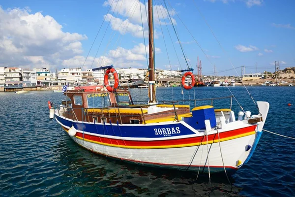 Traditional Greek yacht moored in the harbour with watefront buildings to the rear, Hersonissos, Crete. — Stock Photo, Image