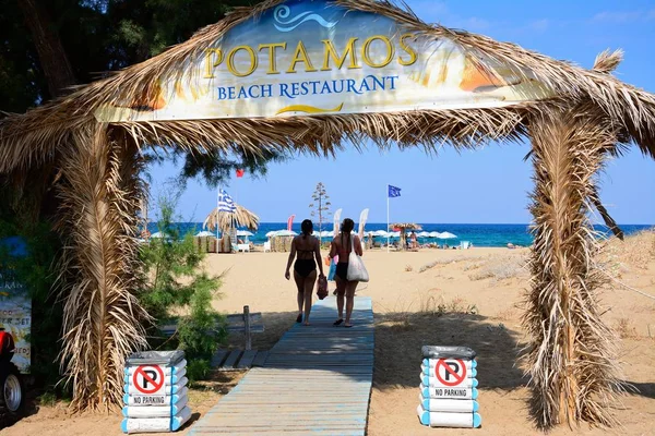 Dos mujeres caminando por el arco de entrada a la playa de Potamos, Malia, Creta . — Foto de Stock