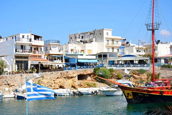 Black Rose Pirate ship moored in the harbour with waterfront restaurants to the rear, Sissi, Crete. — Stock Photo, Image