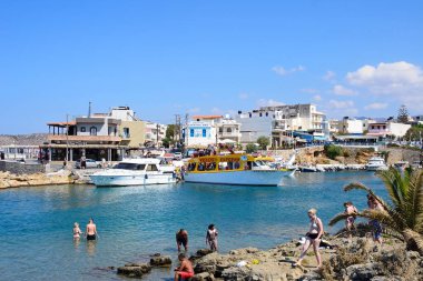 Turistlere tekne ve restoranlar arka, Sissi, Girit için manzaralı kayalık sahil.