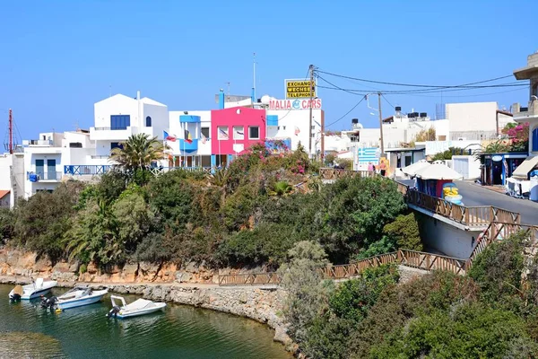 Маленькие лодки пришвартовались в небольшой бухте у гавани с городскими зданиями сзади, на острове Крит . — стоковое фото