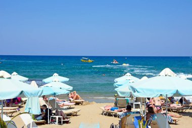 Turistler deniz, Stalida, Crete doğru manzaralı sahilde rahatlatıcı.
