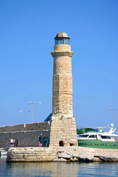 Blick auf den Leuchtturm mit Touristen entlang der Hafenmauer, Rethymno, Beton. — Stockfoto