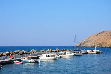 Quayside, Panormos, Crete yürüyen turist ile geleneksel Yunan balıkçı tekneleri limanda palamarla.