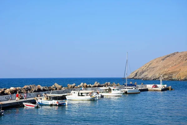Traditional Greek fishing boats moored in the harbour with tourists walking along the quayside, Panormos, Crete. — Stock Photo, Image
