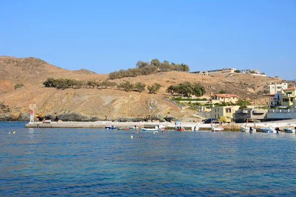 Kleine boten afgemeerd in de haven met uitzicht op de rotsachtige kustlijn, Panormos, Kreta. — Stockfoto