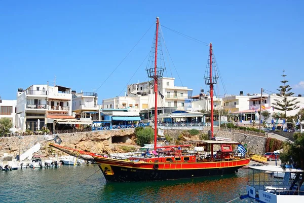 Black Rose piratenschip afgemeerd in de haven met waterkant restaurants aan de achterzijde, Sissi, Kreta. — Stockfoto