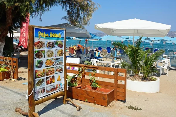 Tablero de menú de restaurante Palm Beach en el borde de la playa con vistas hacia el mar Egeo, Kalyves, Creta . — Foto de Stock