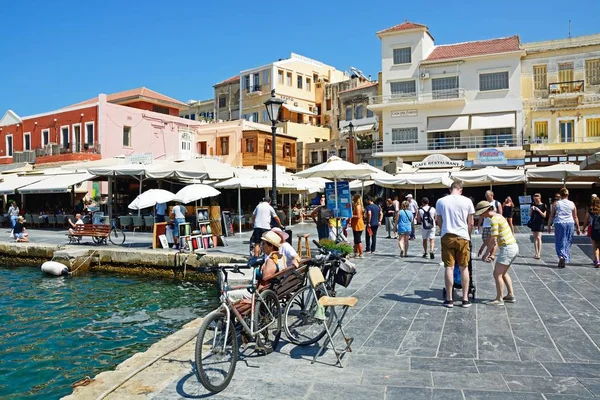 Turistas caminhando ao redor do cais no porto interno com restaurantes e lojas para as traseiras, Chania . — Fotografia de Stock