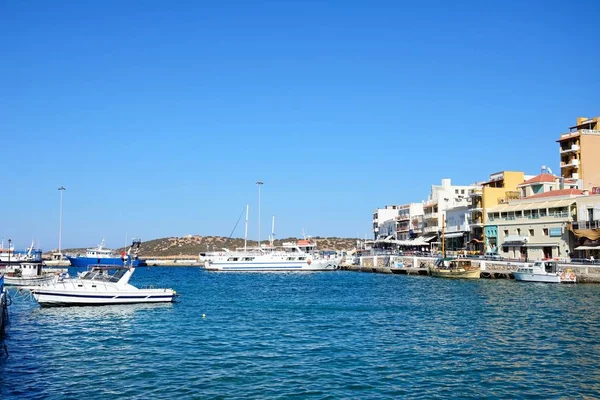 Jachten en boten in de innerlijke haven met waterkant restaurants aan de rechterkant, Agios Nikolaos, Crete. — Stockfoto