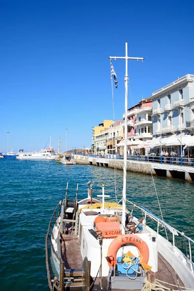Een jacht afgemeerd in de innerlijke haven met waterkant restaurants aan de rechterkant, Agios Nikolaos, Crete. — Stockfoto