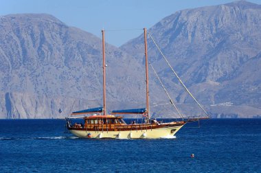 Arkaya, Agios Nikolaos, Crete Bay Dağları ile iki gemi direkleri ile büyük yat.