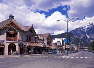 Arka, Banff, Canada dağlara kar ile Banff kasabanın içinden ana cadde boyunca dükkan görünümünü şapkalı.